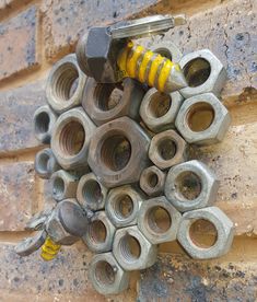 there are many bolts and nuts attached to the side of a brick wall with a wrench on it