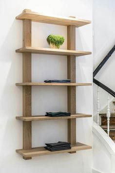 a wooden shelf sitting on the side of a white wall next to a stair case