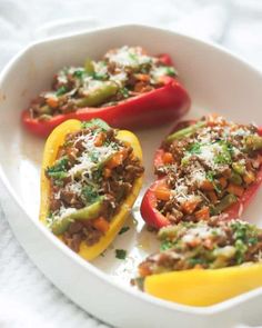 three stuffed peppers in a white dish on a table