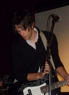 a young man playing an electric guitar in front of a microphone