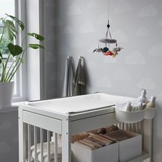 a baby crib in the corner of a room next to a potted plant