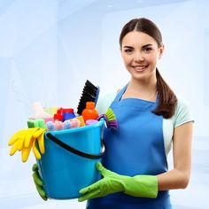 a woman is holding a bucket full of cleaning supplies and smiling at the camera while wearing rubber gloves