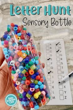 a bottle filled with lots of colorful beads next to a crossword puzzle game on a table