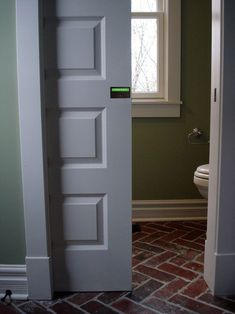 an open door leading to a bathroom with brick flooring