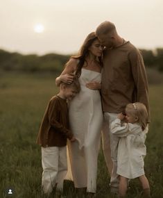 a woman and two children are standing in the grass with their arms around each other