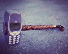 an old cell phone sitting on top of a wooden stick in the middle of concrete