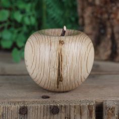 an apple sitting on top of a wooden table next to a green plant in the background