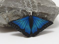 This gorgeous blue morpho pendant necklace in shades of vibrant blue with black and white accents would make a perfect gift for a butterfly lover. I created the image with a process called caning, where different colors of clay are pieces together, reduced down to size, and sliced.  The pendant measures approximately 1 3/4" in size with a black textured backing and an 18 or 20" stainless steel chain. More butterfly items: https://www.etsy.com/shop/PasticheAccessories?ref=hdr_shop_menu&search_query=Butterfly Blue Butterfly Necklace For Gifts, Blue Butterfly Necklace For Gift, Handmade Blue Butterfly Necklace, Polymer Clay Nature, Butterfly Items, Clay Nature, White Polymer Clay, Morpho Butterfly, Blue Morpho