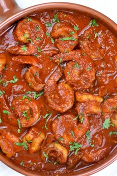 a pan filled with shrimp and sauce on top of a table