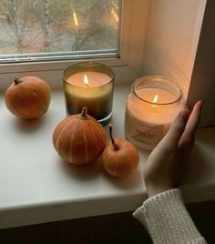 two pumpkins and one candle on a window sill