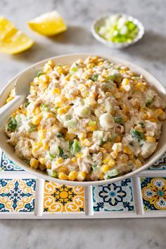 a white bowl filled with corn salad on top of a blue and yellow tile table