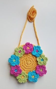 a crocheted flower decoration hanging from a string on a white surface with a yellow cord