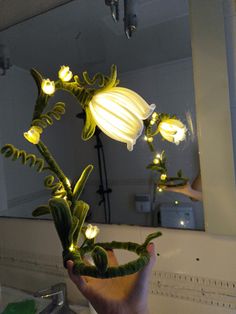 a person holding up a flower with lights on it