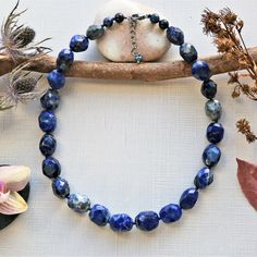 "Necklace length: 18\"L with 1.5\"L extender. Major beads: Lapis lazuli: faceted barrel shaped. Style: Beaded semi-precious stone necklace. Color: Blue color. Clasp: 13MM sterling silver rhodium plated clasp and closed jump ring. Finding: N/A. Workmanship: Hand beaded, and each bead is knotted in dark blue mixed cotton thread. Features: This classic style and timeless necklace feature large faceted lapis lazuli nuggets displaying natural flecks of pyrite that add a hint of shimmer. It is a great Sodalite Gemstone Beads Necklaces, Lapis Lazuli Beaded Necklace With Faceted Beads For Gift, Blue Faceted Oval Beads Jewelry, Spiritual Lapis Lazuli Necklace With Faceted Beads, Adjustable Sapphire Beaded Necklace With Faceted Beads, Adjustable Lapis Lazuli Necklace With Faceted Beads, Blue Lapis Lazuli Crystal Necklaces With Faceted Beads, Blue Lapis Lazuli Crystal Necklace With Faceted Beads, Adjustable Lapis Lazuli Crystal Necklace