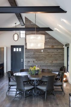 the dining room table is surrounded by gray chairs and wooden paneling, along with a chandelier that hangs from the ceiling