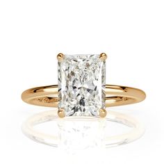 a yellow gold engagement ring with a princess cut diamond in the center, on a white background