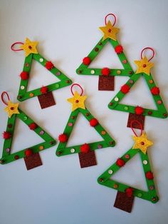 christmas tree ornaments made out of popsicle sticks and colored felt are arranged on a white surface