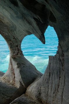 an image of the inside of a rock formation with water and sky in the background