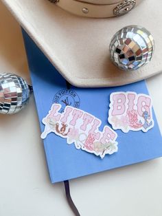 a hat, disco ball and stickers on top of a blue card with the word big sister