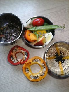 four metal bowls filled with different types of food