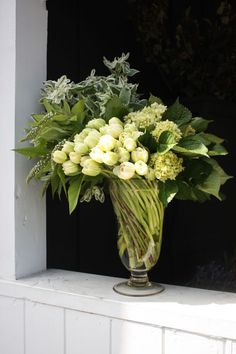 a vase filled with white flowers sitting on top of a window sill