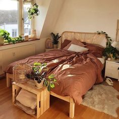 a bed room with a neatly made bed and some potted plants on the table