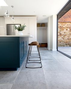 a kitchen with blue cabinets and stools next to an open floor plan that has glass doors on both sides