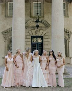 a group of bridesmaids standing in front of a large building with columns on each side