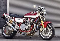 a red and white motorcycle parked in front of a garage door