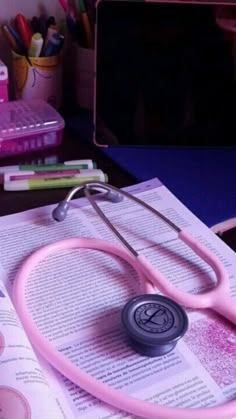 a pink stethoscope sitting on top of an open book