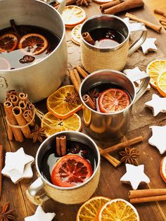 two mugs filled with liquid surrounded by cinnamon and orange slices