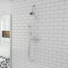 a white tiled bathroom with a shower head and hand held shower faucet in the corner