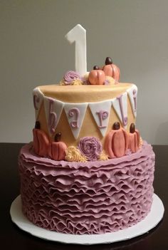 a birthday cake with purple icing and pumpkins on top is one two - year old