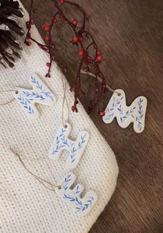 some white and blue ornaments are on a table next to pinecone branches with red berries