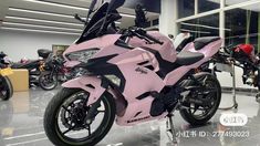 a pink motorcycle is parked in a showroom with other motorcycles and bikes behind it