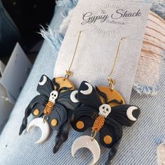 the earrings are decorated with black and white bats, skulls, and crescent moon shapes