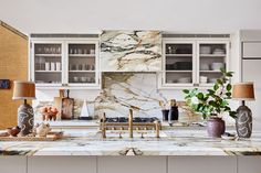 a kitchen with marble counter tops and white cabinets, along with vases on the island