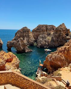 people are sitting on steps overlooking the water and rocks in front of an arch shaped rock formation