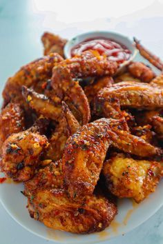 a white plate topped with fried chicken wings and ketchup