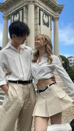 two people standing next to each other in front of a clock tower