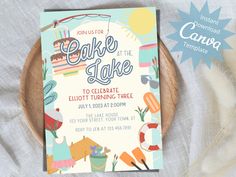 a cake is at the lake birthday party card on a wooden plate with feathers around it