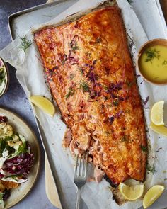 there is a large piece of fish on the table with lemons and other foods