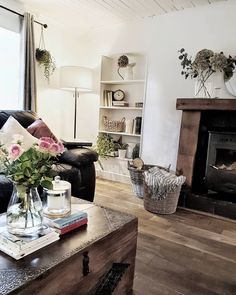 a living room filled with furniture and a fire place next to a window on top of a hard wood floor