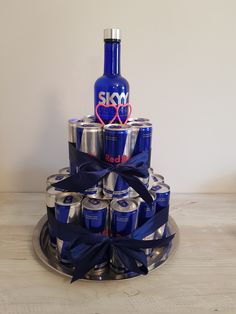 a cake made out of cans with a blue bow on the top and a bottle in the middle