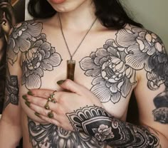 a woman with tattoos on her chest holding a cell phone