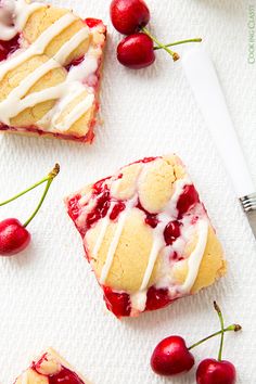 cherry shortcakes with icing and fresh cherries on a white towel next to some cherries