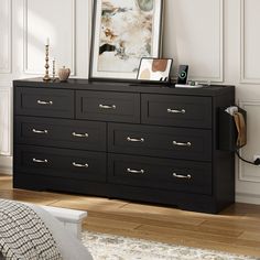 a black dresser with many drawers and pictures on top