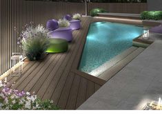 an outdoor swimming pool surrounded by plants and flowers at night with lit candles on the deck