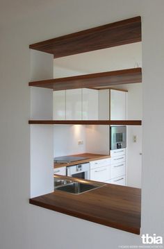 an empty kitchen with white cabinets and wood counter tops, as seen through a window