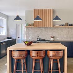 a kitchen with three stools next to an island